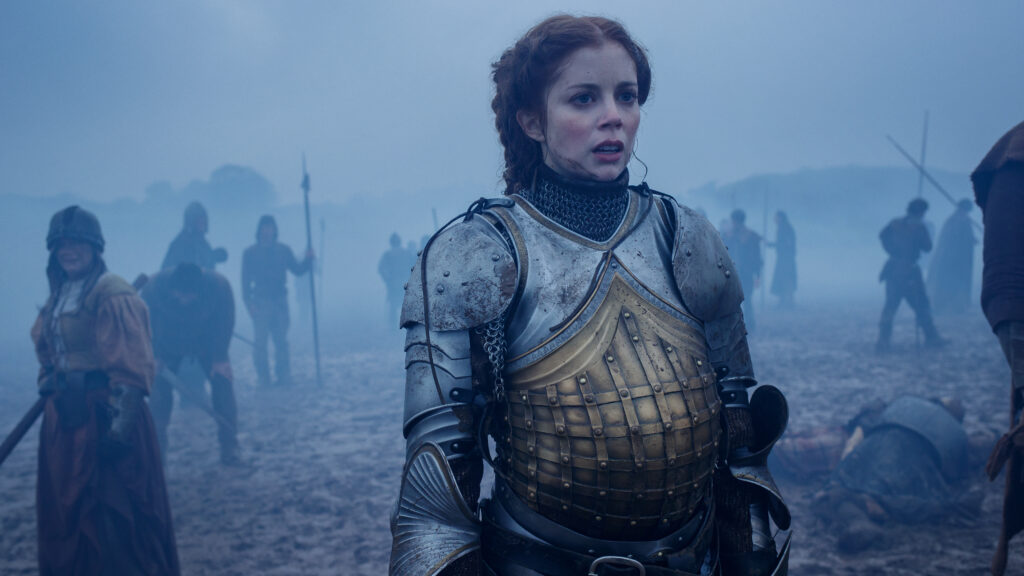 The Spanish Princess Season 2 2020 - viasatepicdrama.com Young female knight in worn metal armor stands in a foggy battlefield among marching soldiers still distant in the haze.